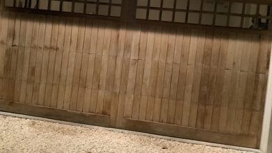 A garage door sitting crooked in its opening