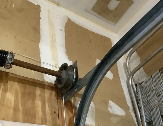A technician checking the spring shaft above a garage door